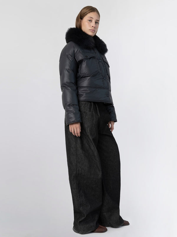 A model showcases a stylish black puffer jacket with a fur collar, paired with wide-leg dark pants, representing MEOTINE's chic aesthetic.