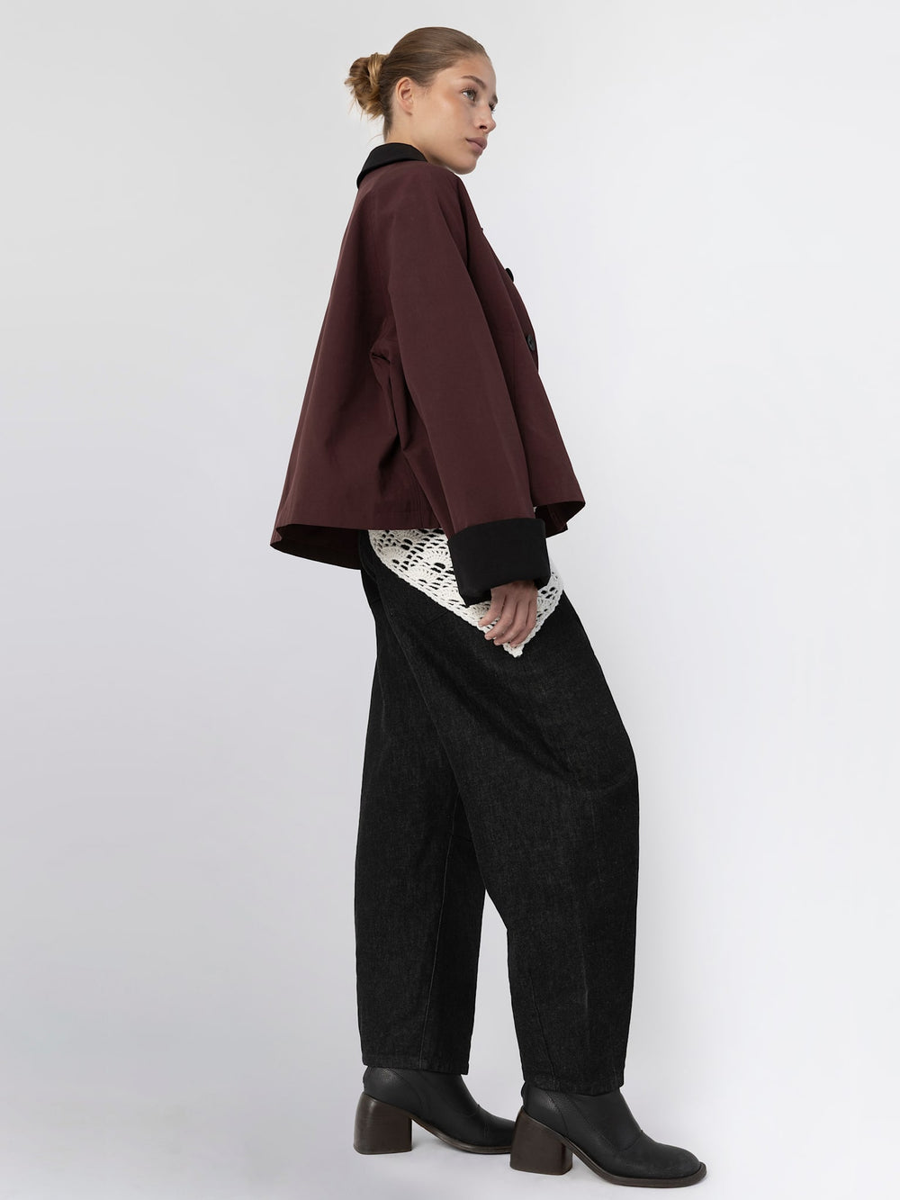 A model showcases a stylish burgundy oversized jacket with a black collar, paired with a white lace top and dark trousers, by MEOTINE.