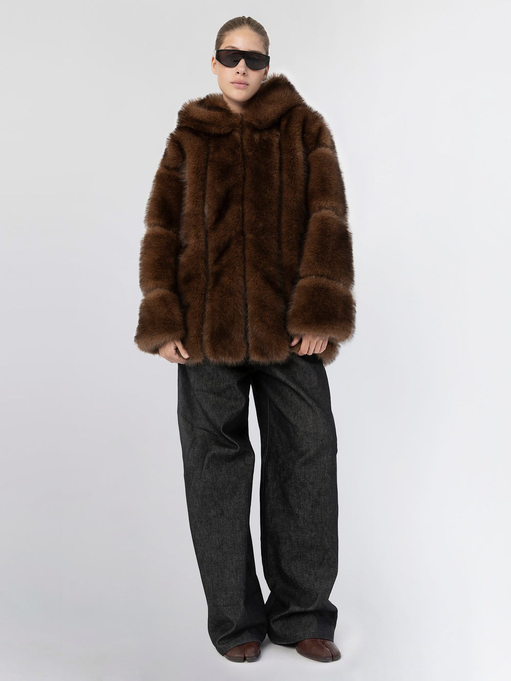 Woman wearing a brown fur coat against a light gray background