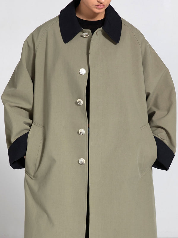 A stylish oversized coat in olive green with a black collar and cuffs, featuring large buttons and side pockets by MEOTINE.