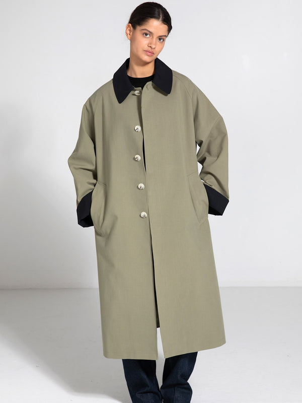 A model wears a stylish olive green coat with a black collar and pockets, showcasing MEOTINE's modern design.