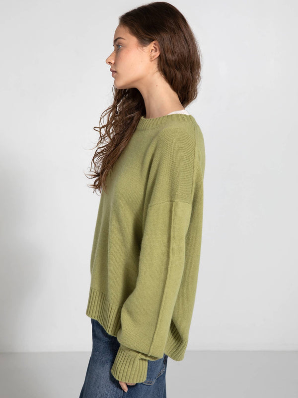 A model showcases a relaxed-fit, light green sweater by MEOTINE, paired with blue jeans, highlighting a casual style.