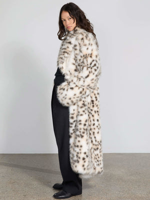 A model showcases a stylish MEOTINE faux fur coat with a spotted pattern, paired with sleek black pants against a neutral backdrop.