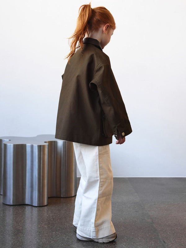 A child wearing a stylish brown jacket and white wide-leg pants, showcasing a modern look by MEOTINE.