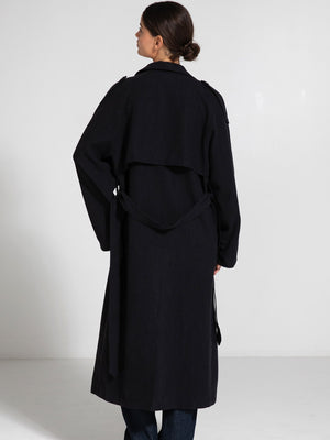 A woman in a stylish black trench coat with a flowing design, showcasing the back view, perfect for a chic look by MEOTINE.