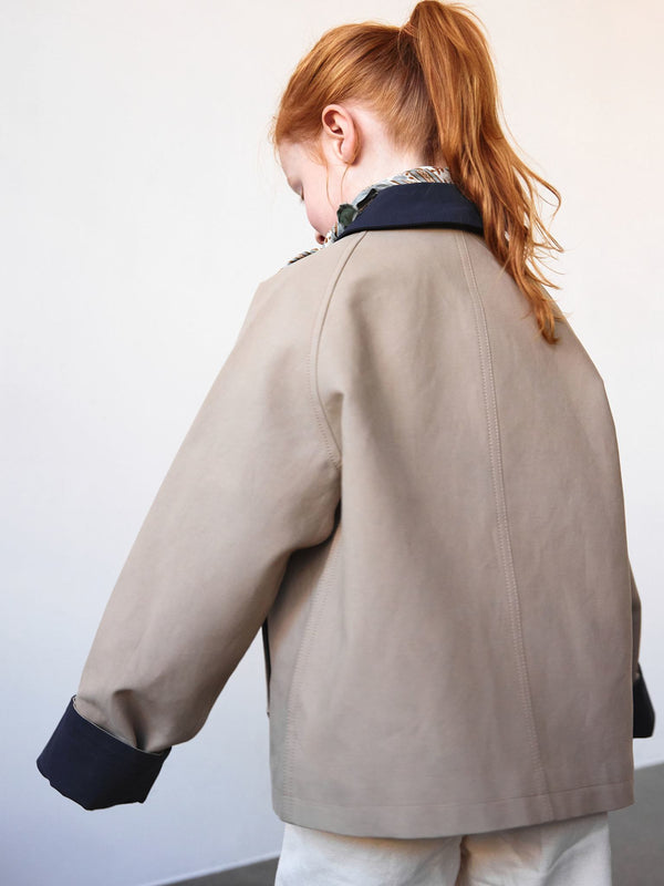 Stylish beige jacket with a navy collar, perfect for kids. Features a relaxed fit and pairs well with various outfits. MEOTINE.