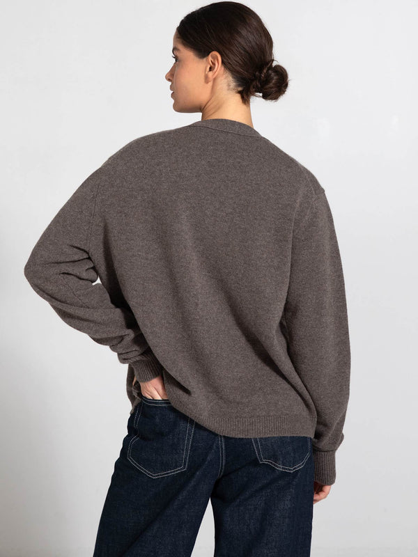A model wearing a cozy brown sweater from MEOTINE, showcasing a relaxed fit and soft texture, viewed from the back.