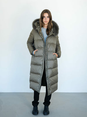 Stylish long olive green puffer coat with a fur-lined hood, perfect for winter, by MEOTINE. Model stands against a plain background.
