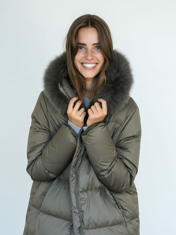 A smiling woman in a cozy olive green puffer jacket with a fur-lined hood, showcasing MEOTINE's stylish winter outerwear.