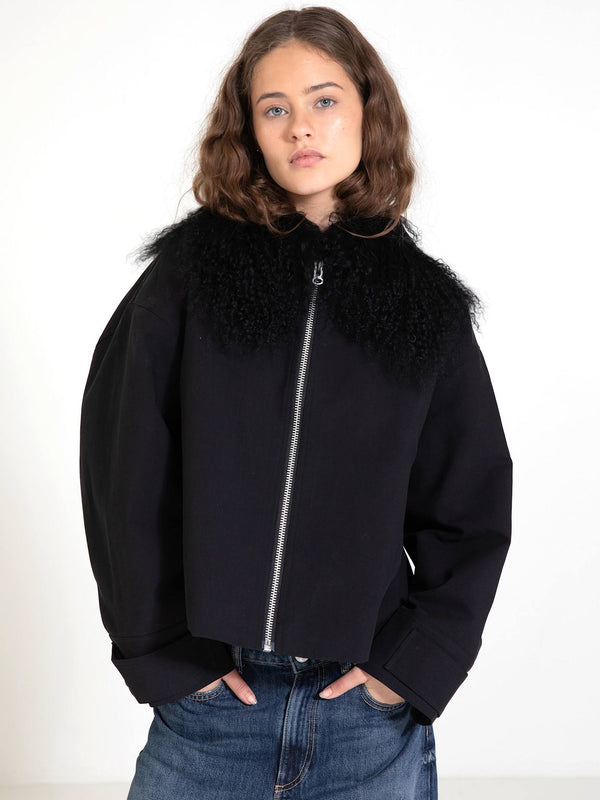 A model showcases a stylish black cropped jacket with a fluffy collar, embodying modern fashion by MEOTINE.