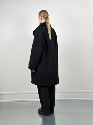A model showcases a stylish black oversized coat from MEOTINE, featuring a relaxed fit and a classic collar, viewed from the back.