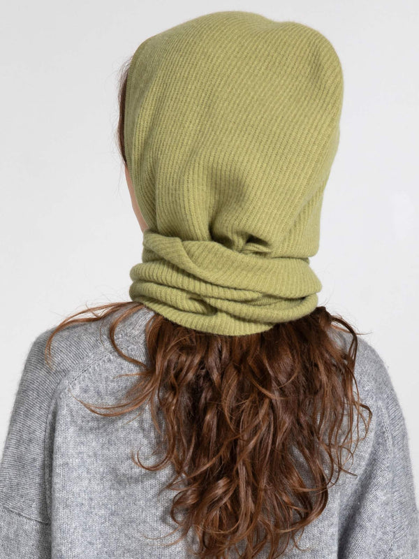 A model with long, wavy hair wears a soft, olive green ribbed beanie and neck warmer from MEOTINE, showcasing cozy winter style.