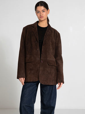 A model wears a brown suede blazer with a relaxed fit, paired with dark denim pants, showcasing MEOTINE's stylish design.