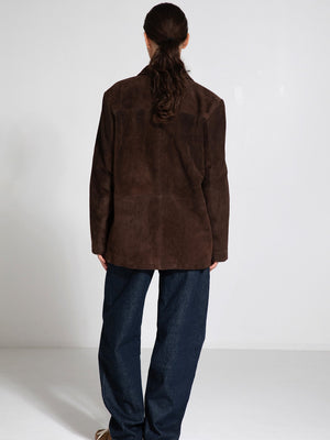 A model wearing a brown suede oversized jacket paired with loose denim pants, showcasing a relaxed and stylish look. MEOTINE.
