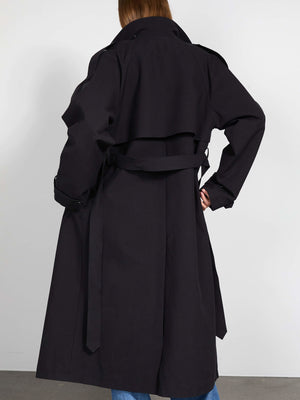 A model showcases a stylish black trench coat from MEOTINE, featuring a belted waist and a classic silhouette, viewed from the back.