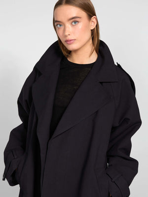 A model showcases a stylish black oversized coat from MEOTINE, featuring a wide collar and relaxed fit, perfect for layering.