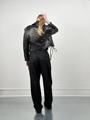 A model showcases a stylish black leather jacket with a relaxed fit, paired with high-waisted black trousers, by MEOTINE.