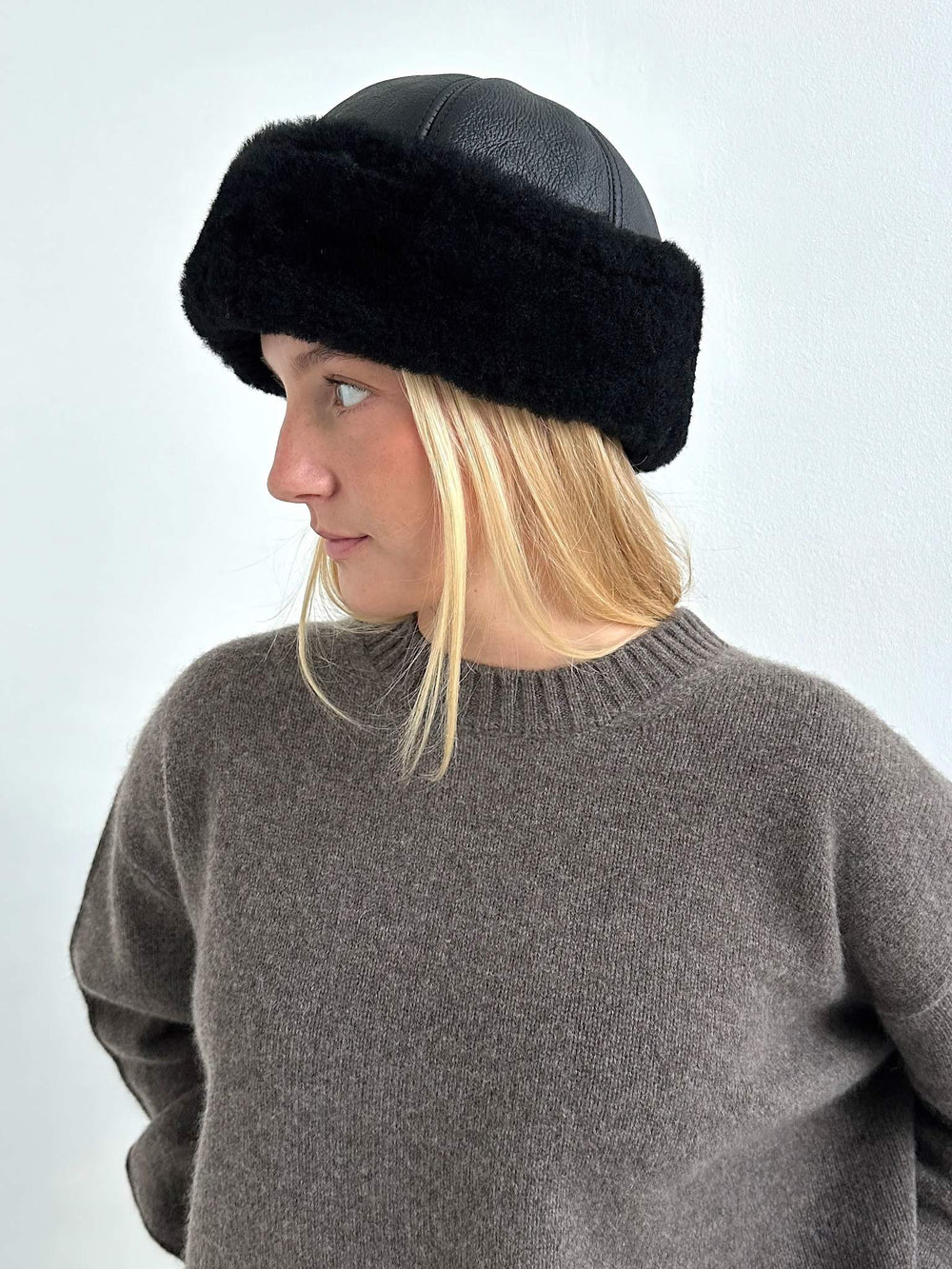 A young woman models a stylish black hat with a fur band, paired with a cozy brown sweater, showcasing MEOTINE's chic design.