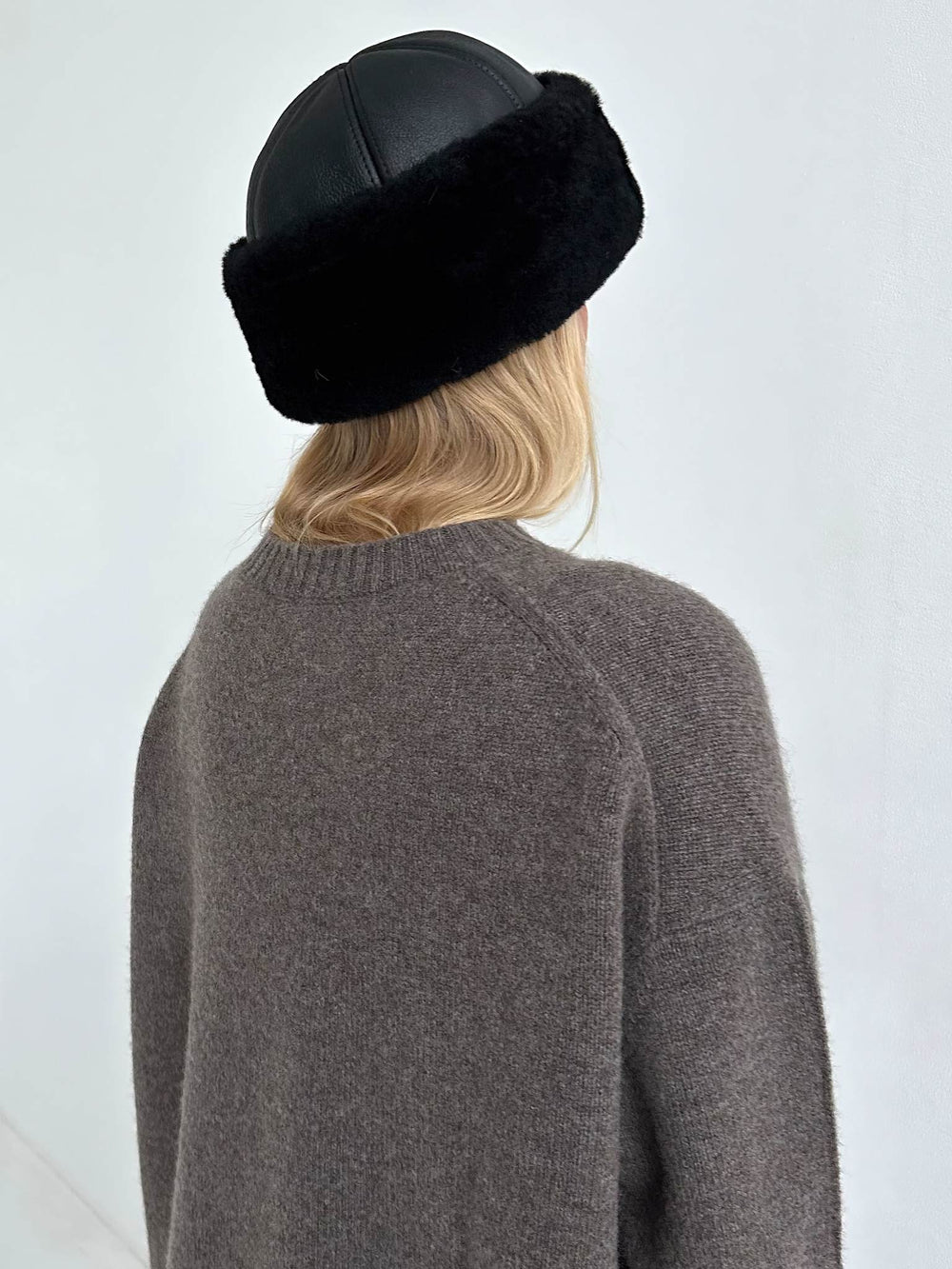A young woman models a stylish black hat with a fur band, paired with a cozy brown sweater, showcasing MEOTINE's chic design.