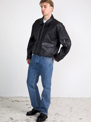 A model wearing a black leather bomber jacket paired with blue jeans and black shoes, showcasing MEOTINE's stylish outerwear.
