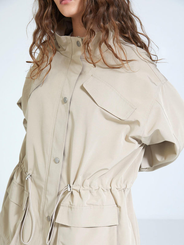 Beige oversized jacket with a drawstring waist and large pockets, showcasing a stylish and modern design by MEOTINE.
