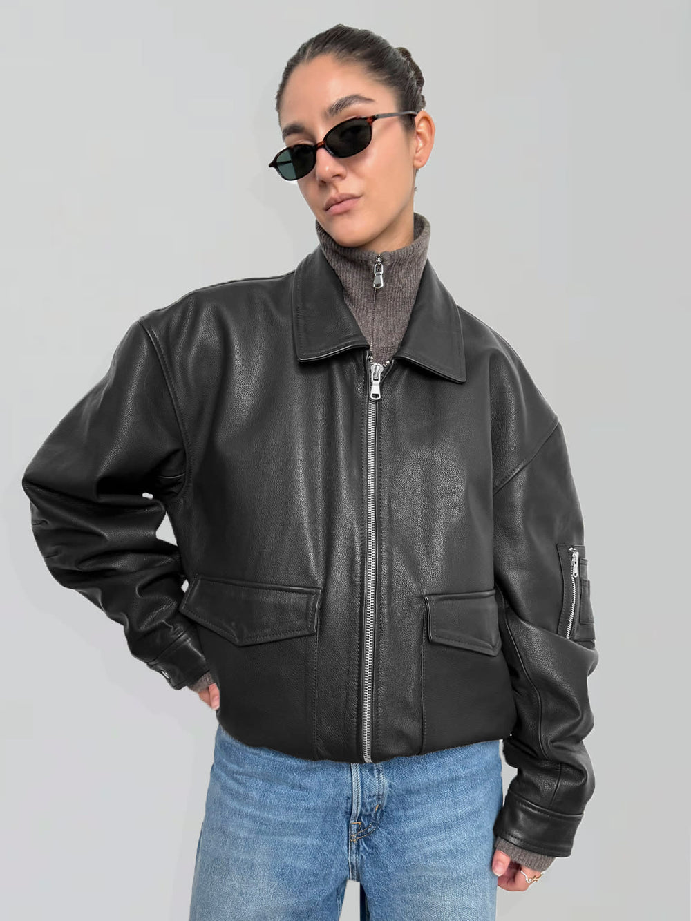 A model showcases a stylish black leather jacket from MEOTINE, paired with a turtleneck and trendy sunglasses.