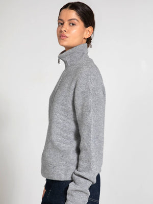 A model showcases a stylish gray ribbed sweater with a high collar, perfect for a chic, cozy look by MEOTINE.
