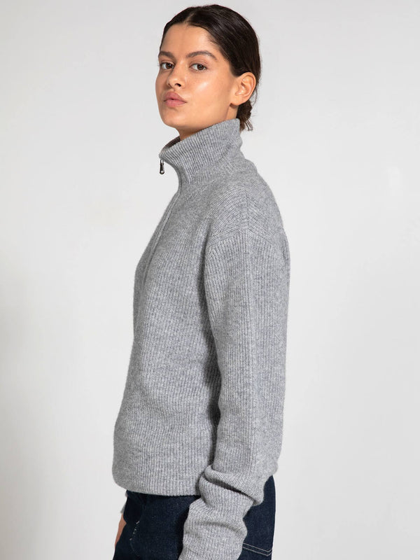 A model showcases a stylish gray ribbed sweater with a high collar, perfect for a chic, cozy look by MEOTINE.