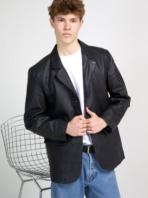 Stylish black leather blazer worn by a model, paired with a white t-shirt and blue jeans, showcasing MEOTINE's modern design.