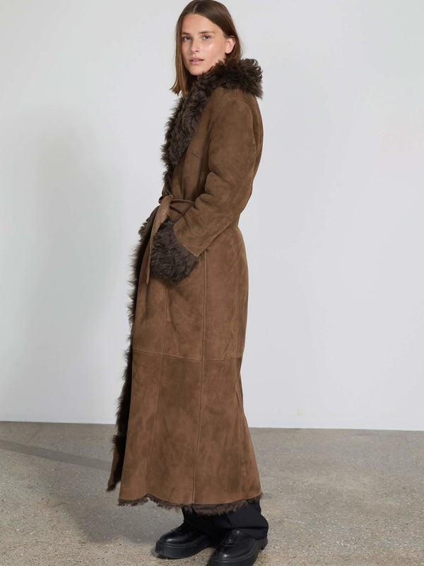 A model showcases a stylish brown suede coat with a fur collar and cuffs, embodying the elegance of MEOTINE fashion.