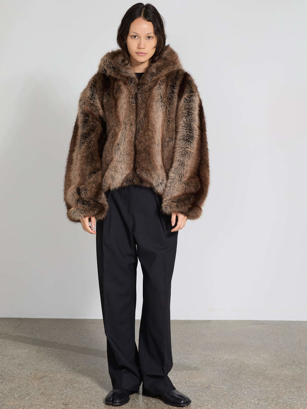 A model wears a luxurious brown faux fur jacket with a hood, paired with black trousers, showcasing MEOTINE's elegant style.