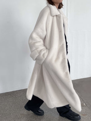 A model wears a cozy, oversized white MEOTINE coat, styled with black pants, showcasing a chic and modern look.
