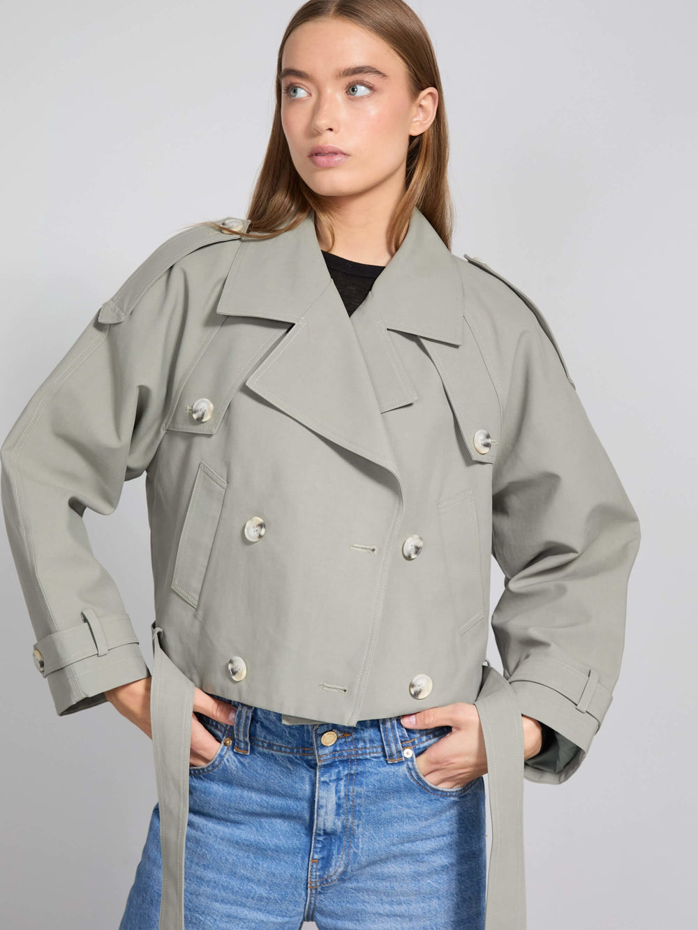 Stylish cropped trench coat in light gray, featuring double-breasted buttons and a belted waist, perfect for a chic look by MEOTINE.
