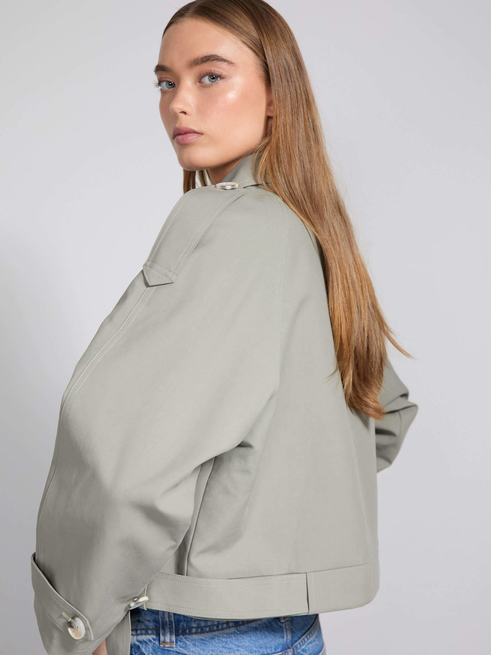 Stylish cropped trench coat in light gray, featuring double-breasted buttons and a belted waist, perfect for a chic look by MEOTINE.