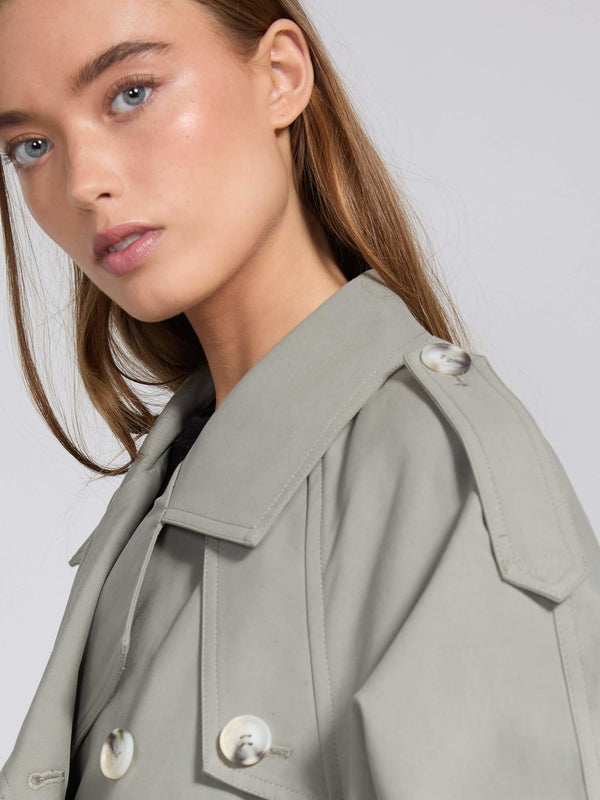 A close-up of a model wearing a light gray trench coat with a stylish collar and button details, showcasing MEOTINE's elegant design.