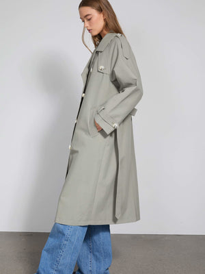 A stylish light gray trench coat with a relaxed fit, featuring large buttons and side pockets, perfect for a chic look by MEOTINE.