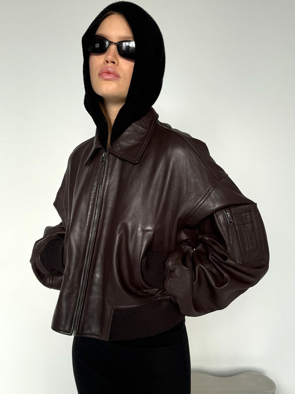 Stylish model wearing a brown leather cropped jacket with a hood and sunglasses, showcasing MEOTINE's modern design.