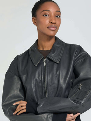 A model showcases a stylish black leather jacket with a zip closure and oversized sleeves, representing MEOTINE's modern aesthetic.