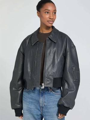 A model wears a stylish black cropped leather jacket with a zip closure and oversized sleeves, paired with high-waisted jeans. MEOTINE.