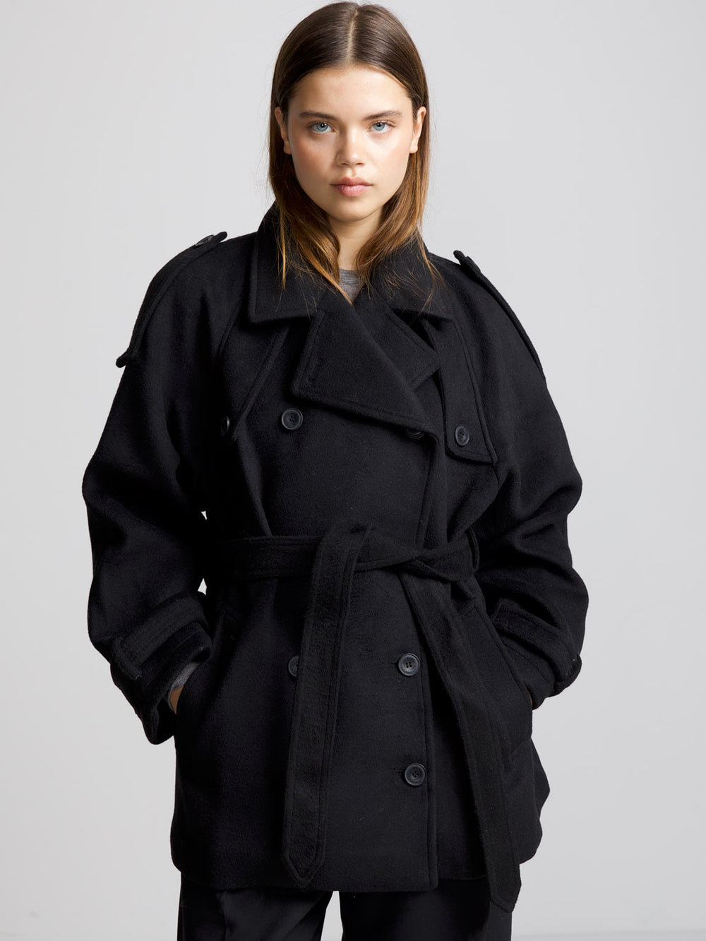 A model wears a stylish black oversized coat with a belt, showcasing a chic and modern look by MEOTINE.
