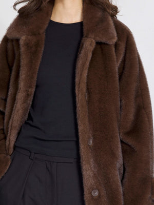 Brown faux fur coat with a classic collar, featuring a button closure, styled over a black top, perfect for a cozy look by MEOTINE.