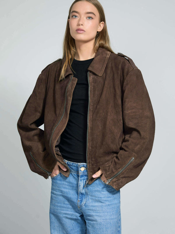 Brown oversized jacket with a relaxed fit, featuring a zip closure and side pockets, styled with a black top and blue jeans. MEOTINE.