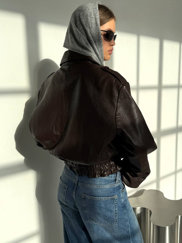 A model showcases a stylish brown leather jacket paired with a gray hoodie and denim jeans, embodying MEOTINE's chic aesthetic.