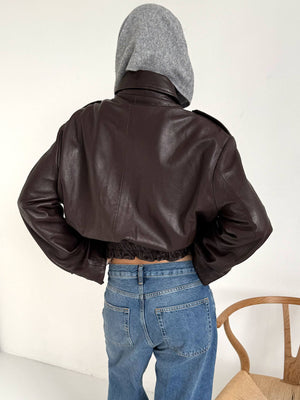 Stylish brown cropped leather jacket with a hood, paired with high-waisted jeans, showcasing a modern look by MEOTINE.