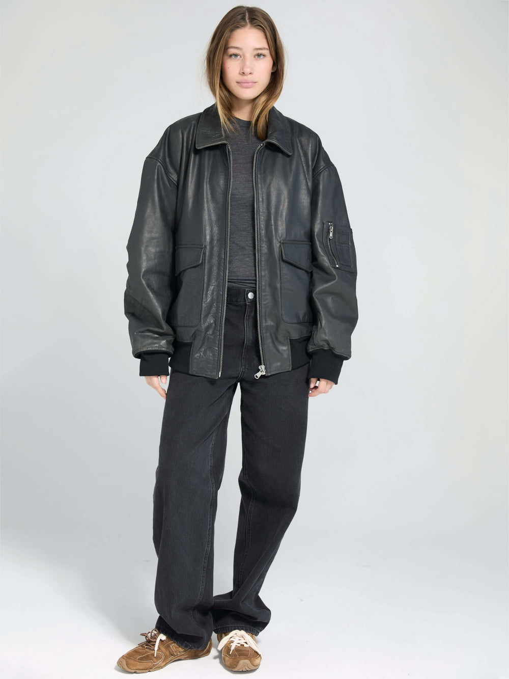 Oversized black leather jacket with front pockets, styled casually, perfect for a trendy look by MEOTINE.