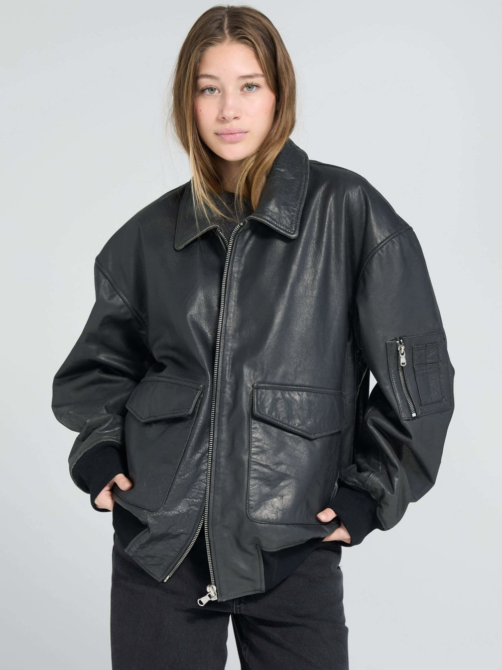 Oversized black leather jacket with front pockets, styled casually, perfect for a trendy look by MEOTINE.
