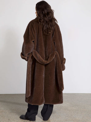 A model showcases a luxurious brown faux fur coat from MEOTINE, featuring a belted waist and a cozy, oversized fit.