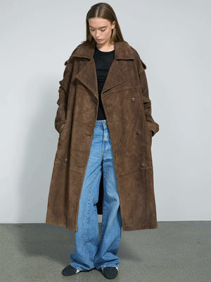 A model showcases a stylish brown suede trench coat by MEOTINE, paired with wide-leg jeans and a black top, set against a neutral backdrop.