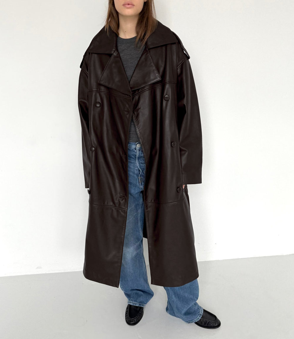 A model showcases a stylish brown leather trench coat paired with casual blue jeans, embodying modern fashion by MEOTINE.