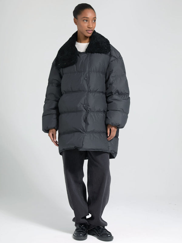 Stylish black puffer coat with a plush collar, worn by a model in casual attire, showcasing MEOTINE's modern winter fashion.